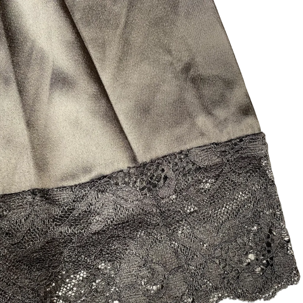 Close-up of black lace trim on a garment against a neutral background